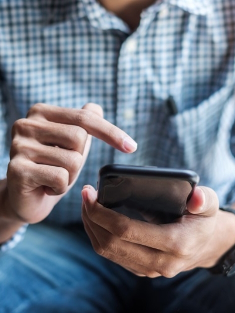 Young casual Businessman holding and using smartphone for sms messages, hipster man typing touchscreen cell phone in the cafe. business, lifestyle, technology and Social media network concept